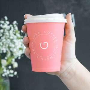 person holding pink and white disposable coffee cup